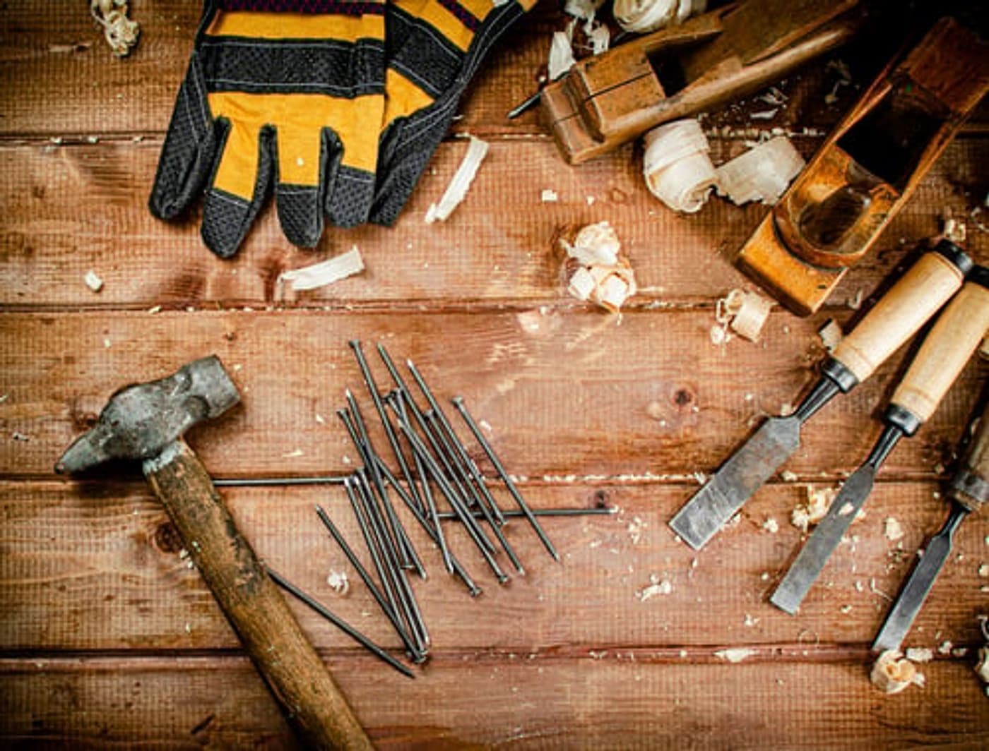 Carpentry hand tools, gloves and nails laid out on a workbench at G&I B Construction
