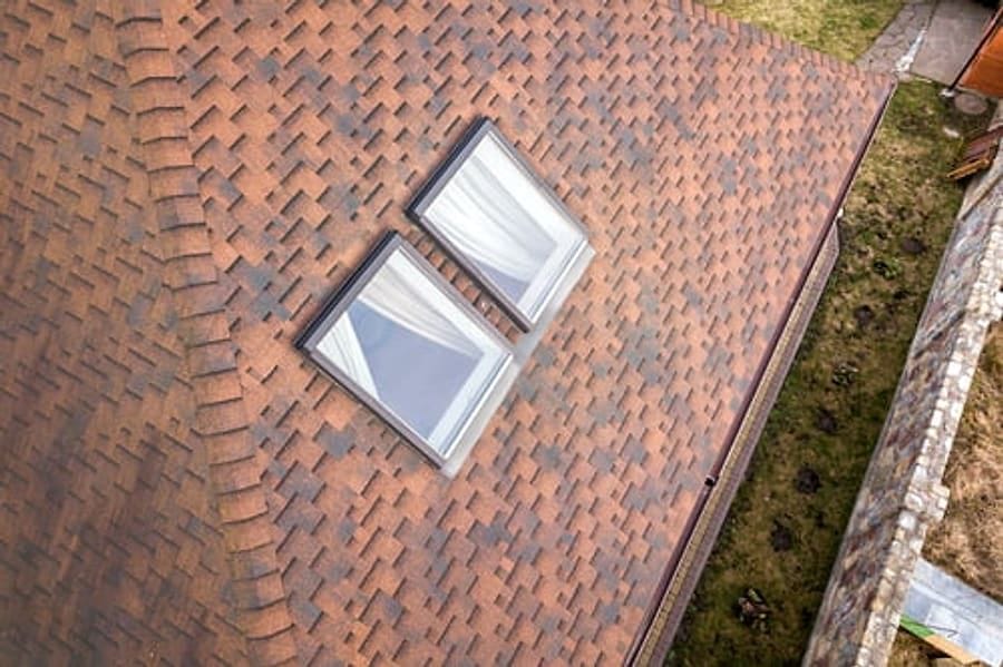 Aerial view of a shingle roof with two skylights and clean gutter line