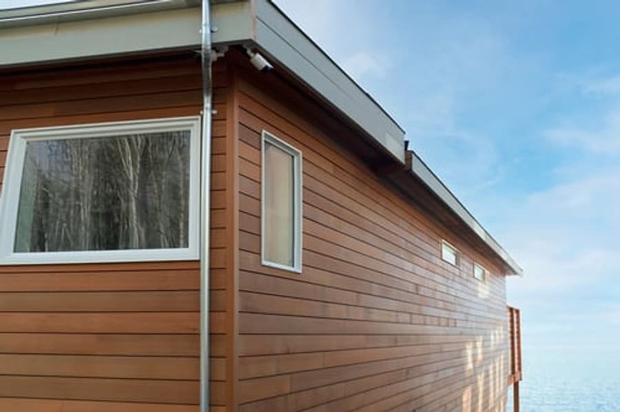 Modern horizontal wood-tone siding with white window trim on a clean building exterior